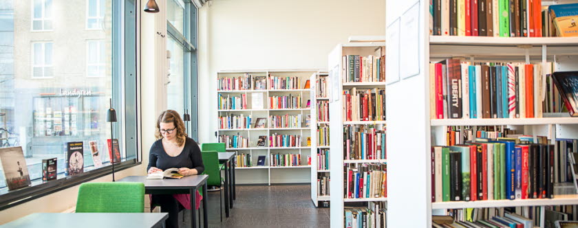 Kvinna sitter och läser vid en av studieplatserna på Bara bibliotek. Foto: TA Fotografi